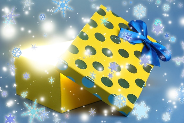 Gift box with bright light on it on blue background