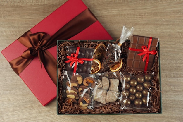 Gift box with chocolate and sweets on wooden table top view