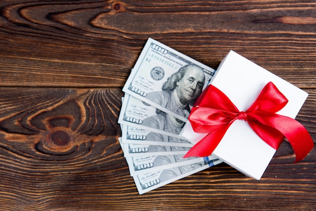 Gift box with dollars on wooden board