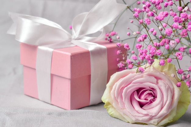 Gift box with flowers on pink Valentine's Day background.