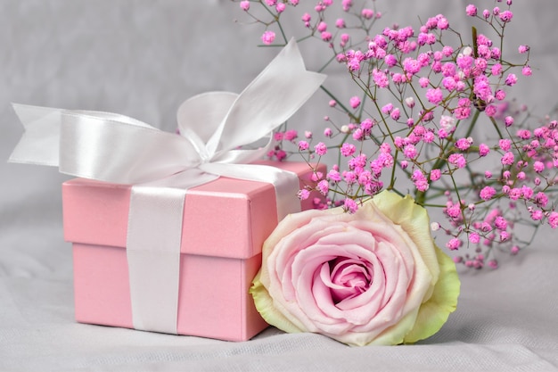 Gift box with flowers on pink Valentine's Day background.