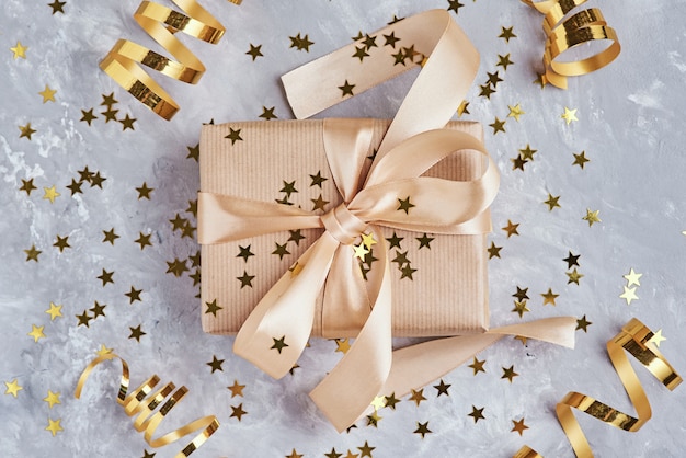 Gift box with golden bow and confetti, close up