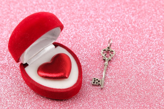 Gift box with key and red hearts closeup on a bright shiny pink background Valentines Day