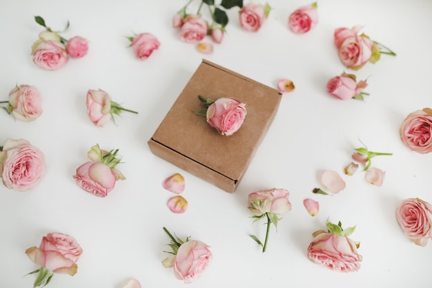 Gift box with pink rose flowers on white background