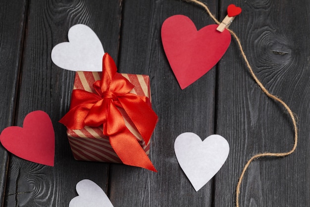 Gift box with red bow ribbon and  paper hearts for Valentines day