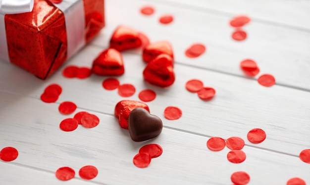 Gift box with a red chokolate shape of heart on white wooden Valentines background Greeting card banner