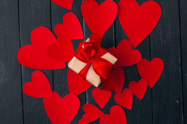 Gift box with red hearts on wooden table