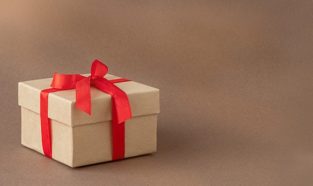 Gift box with red ribbon on brown background