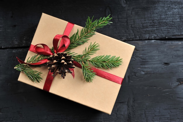 Gift box with red ribbon, fir branch and cone