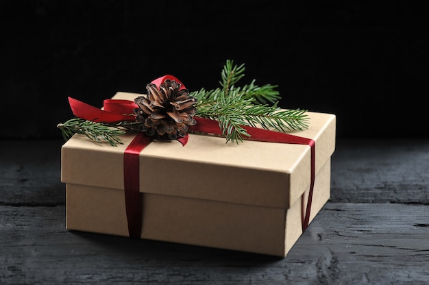 Gift box with red ribbon, fir branch and cone