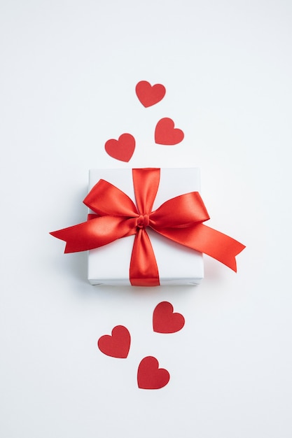 Gift box with red ribbon and hearts on white