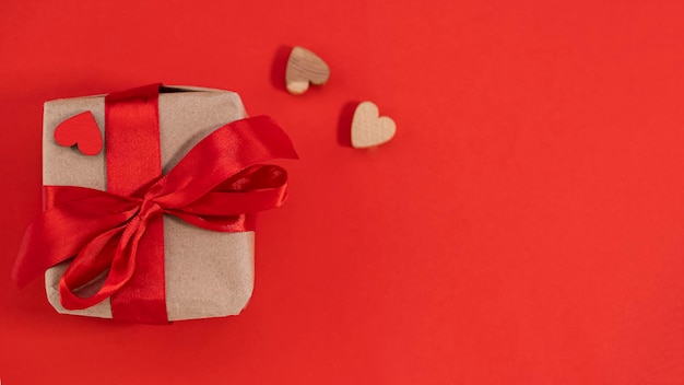 Gift box with red ribbon on red background with copy space