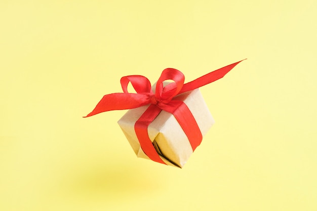 Gift box with red ribbon on yellow 