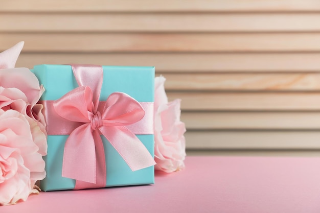 Gift box with roses flowers on pink table Mothers day spring concept