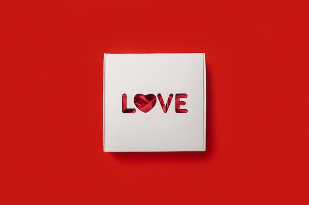 Gift box with the text Love on a red background. Composition Valentine's Day. Banner. Flat lay, top view.