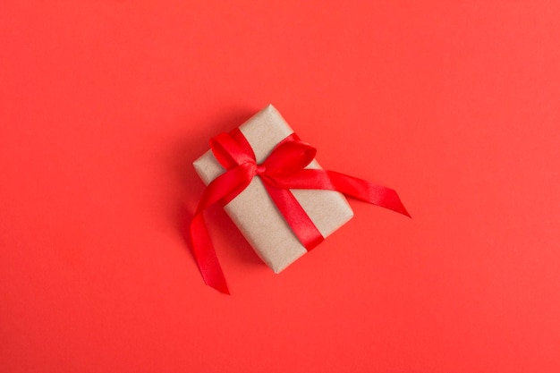 Gift box with tied red bow on the red  background. Top view. Copy space.