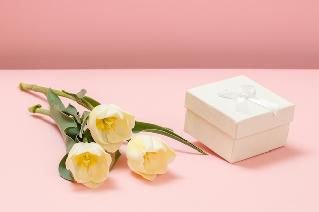 Gift box with tulip flowers on a pink background