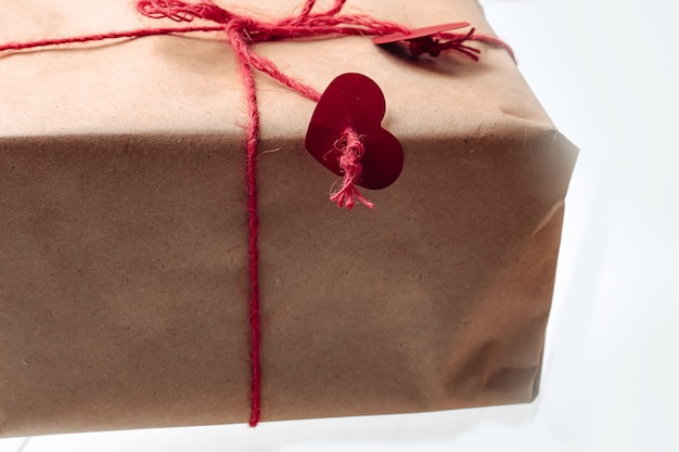 Gift box wrapped in kraft, tied with a rope with hearts. Eco-friendly biodegradable packaging. DIY wrapped gift.