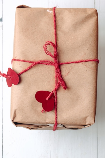 Gift box wrapped in kraft, tied with a rope with hearts. Eco-friendly biodegradable packaging. DIY wrapped gift.