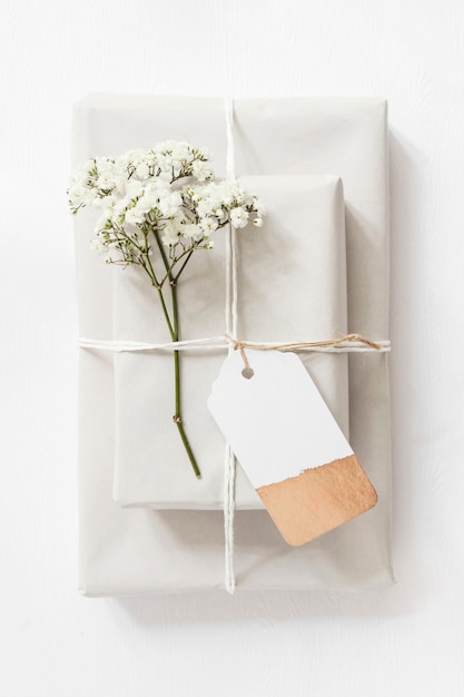 Gift boxes and baby's-breath flower twig tied together with string and tag