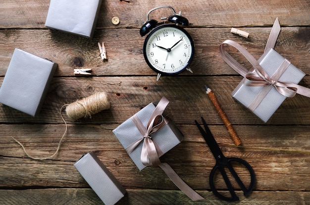 Gift boxes, black alarm clock, pen, scissors on wooden. 