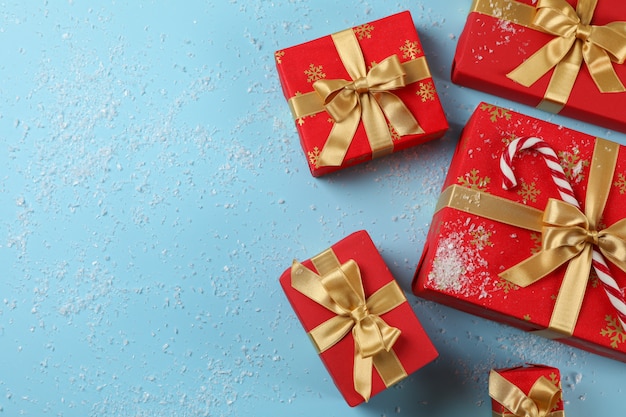 Gift boxes, candy cane and snow on blue background, copy space