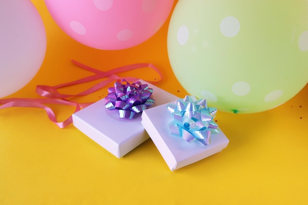 Gift boxes decorated with a bow of shiny ribbon, holiday balloons, surprise, happy birthday