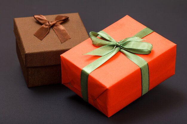 Gift boxes tied with green and brown ribbons on black background. Celebration day concept.