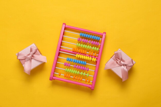 Gift boxes and toy abacus on yellow background