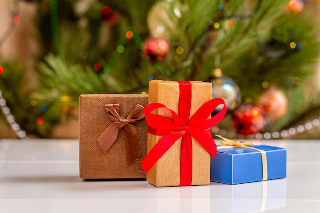 Gift boxes with bows and blurred Christmas tree with twinkling party lights and toy balls