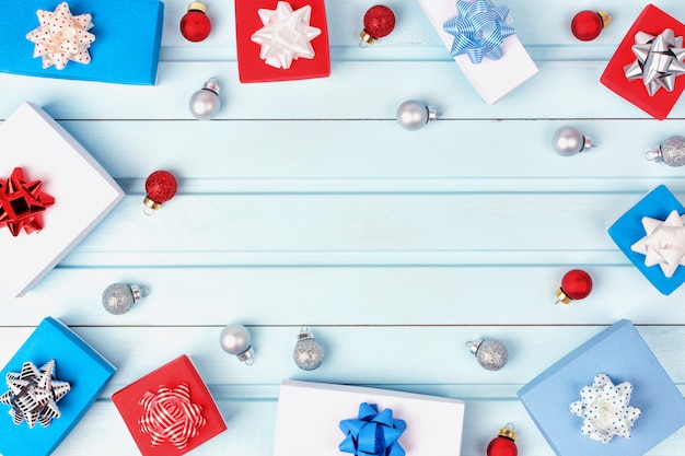 Gift boxes with bows and Christmas balls are lined up in a circle on blue 