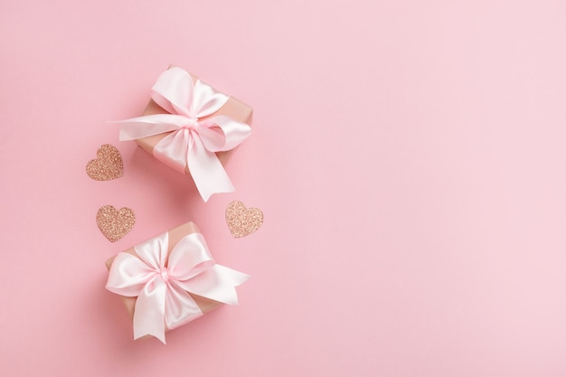 Gift boxes with pink ribbon and hearts on pastel pink background