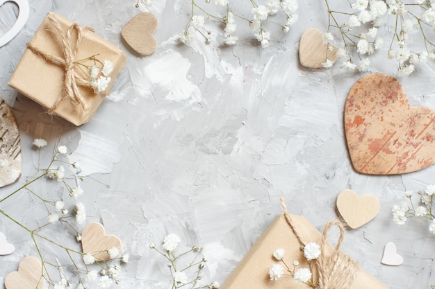 Gift boxes with small white flowers and hearts on a grey background