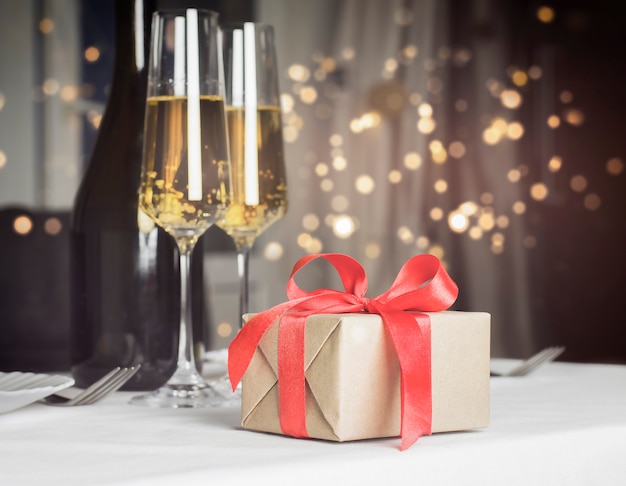 Gift and glasses of champagne with defocus lights wall