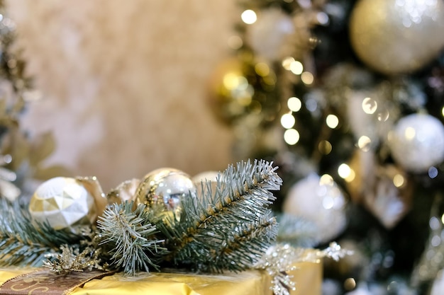 Gift in a gold box near the Christmas tree. Bokeh. Background. Calm colors, close-up.