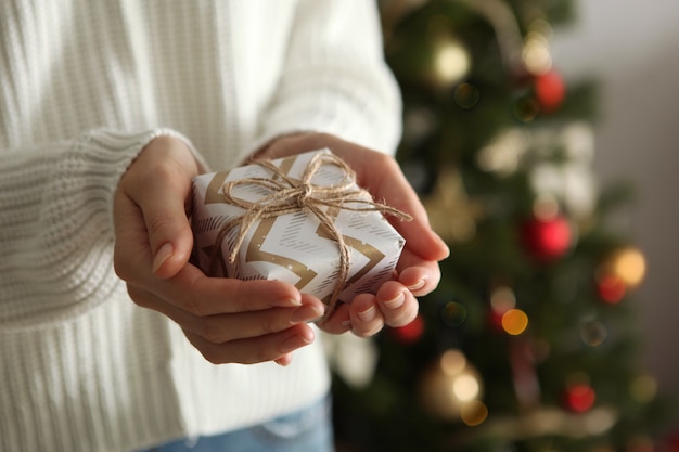 Gift in hands for christmas or new year on a background of a decorated interior