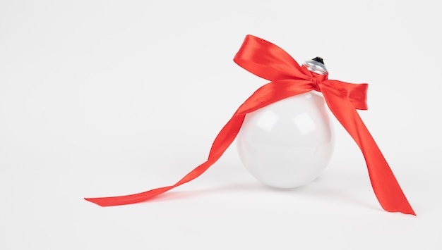 Gift idea concept. Lightbulb with red bow on white background with copy space. High quality photo