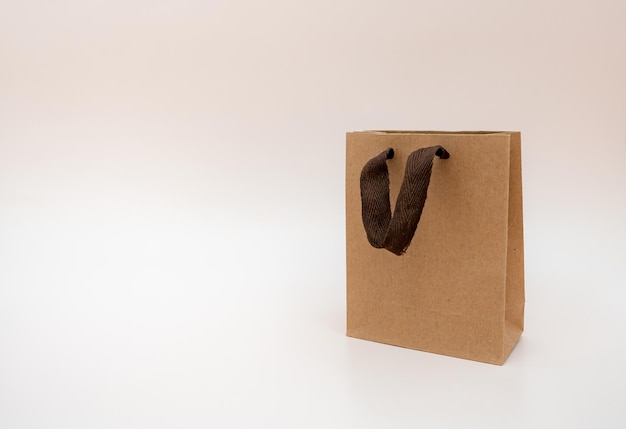 Gift kraft package isolated on a light background kraft bag with brown hands the concept of recycling gifts shopping discounts