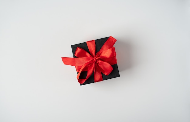 A gift tied with red ribbon on the light (white) background. Valentine's day concept. Flat lay, top view.