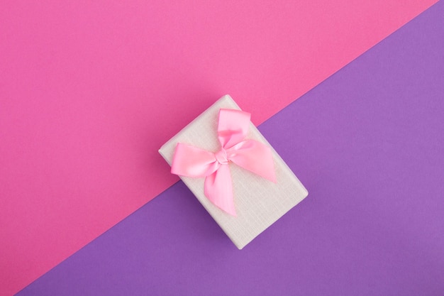 Gift with pink bow on the colorful table.Top view.Copy space.