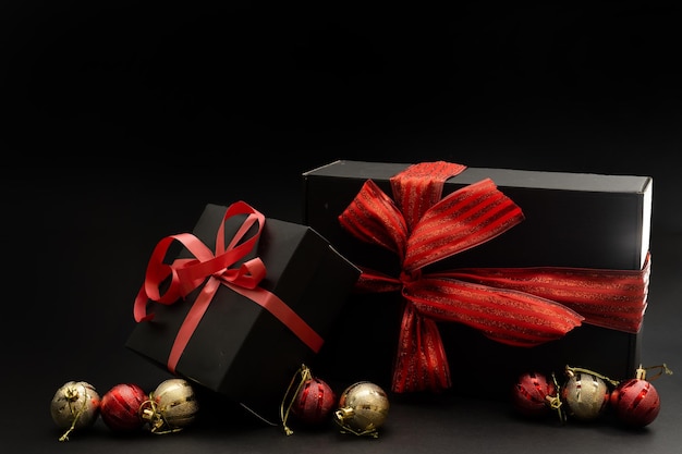 Gift wrapped in dark black paper with luxury bow on dark background. Horizontal with copy space.