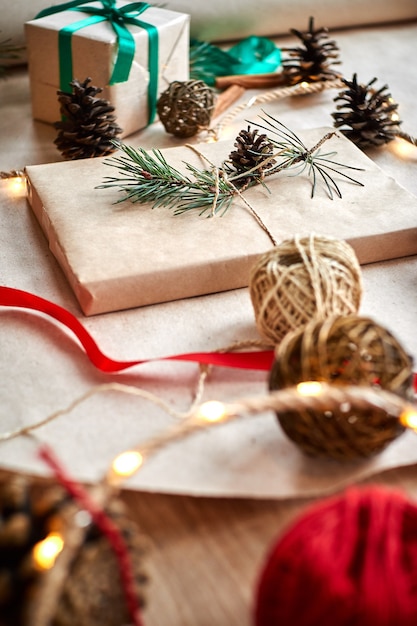 gift wrapping in craft paper tied with twine rope and decorated with a fir branch with a cone