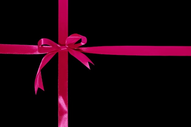 Gift wrapping design with pink ribbons and bow isolated on black background