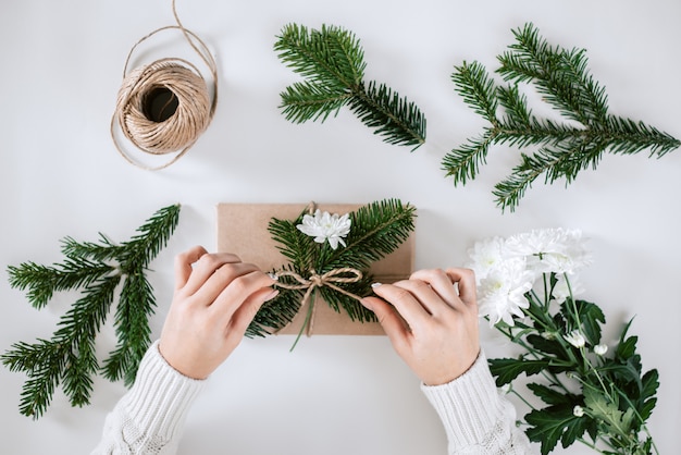 Gift wrapping with natural paper, fir and white flower.