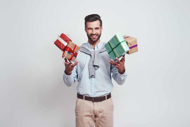 Gifts boom cheerful young man is holding gifts and feeling so happy standing on a