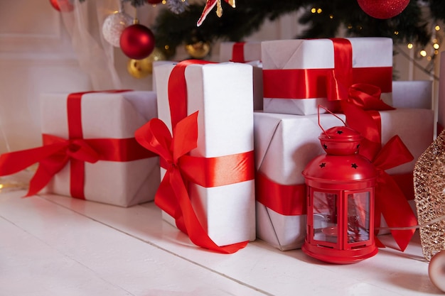 Gifts under the Christmas tree in white boxes, tied with a red ribbon.