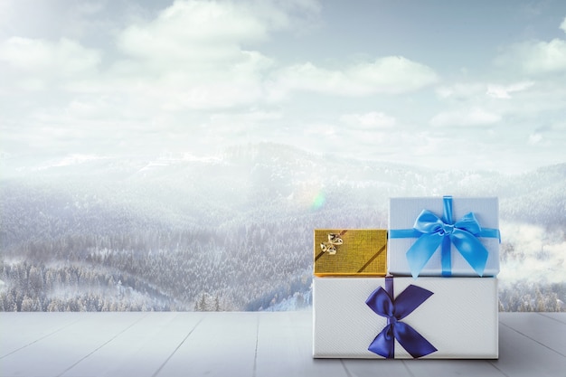 Gifts for family or friends and landscape of mountains on background. Boxes and parfumes in front of snowly mountains and cloudly sky. Winter day, holidays, travel, New Year and Christmas time. .