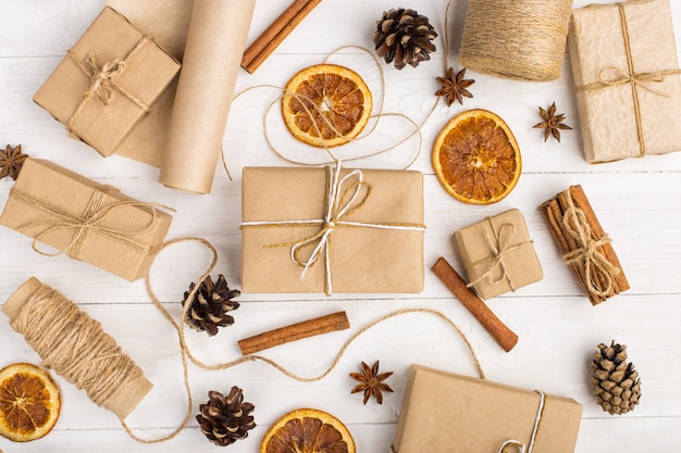 Gifts from craft paper, dried orange, cinnamon, pine cones, anise on a white table