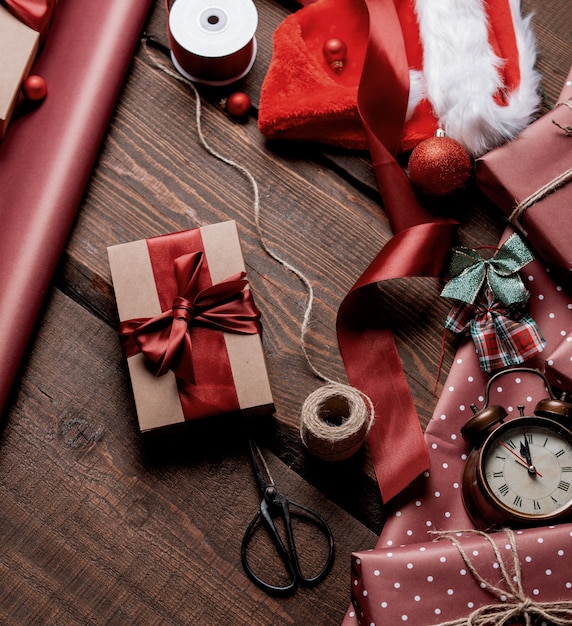 Gifts and red paper in wrapping time on wooden table