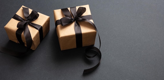 Gifts with black ribbon against black background Black Friday concept